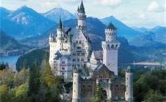 an image of a castle that is in the middle of some trees and mountains behind it