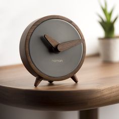 an alarm clock sitting on top of a wooden table next to a potted plant