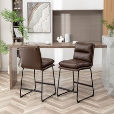 two brown leather chairs sitting at a wooden table