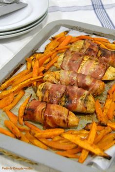 chicken wrapped in bacon and sweet potato wedges on a baking sheet with other food items