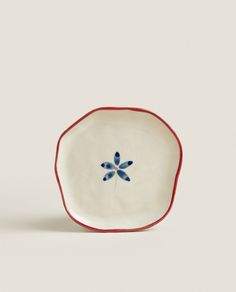 a white and red plate with blue flowers on the rim, against a gray background