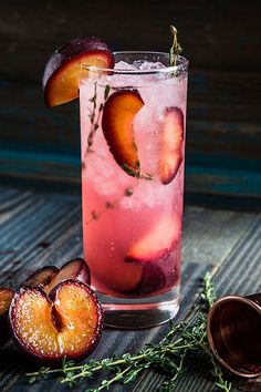 a glass filled with ice and fruit next to sliced peaches on top of a wooden table