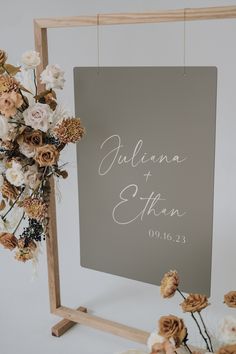 a sign that says juliana and etan with flowers hanging from it's frame