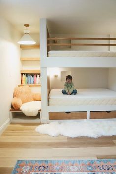 a young boy sitting on top of a bunk bed in a room with hardwood floors