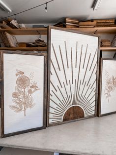 three framed art work displayed on top of a table