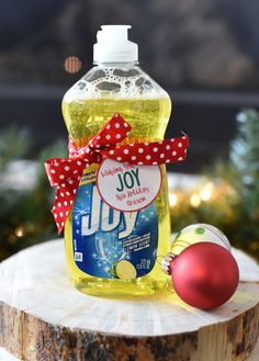 a bottle of joy liquid sitting on top of a tree stump next to a christmas ornament