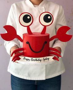 a woman holding a red cake decorated like a crab