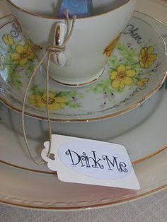 there is a tea cup and saucer on the plate with a tag that says drink me