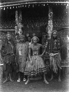 an old black and white photo of three women in native dress standing outside a hut