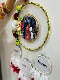 a person holding up a picture frame with flowers and feathers around it that says beena