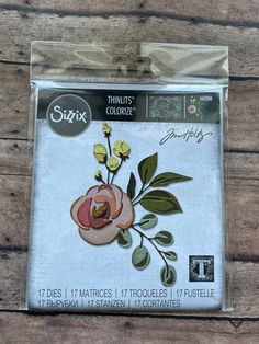 the package is packaged in plastic and has flowers on it with green leaves, which are also embroidered onto fabric