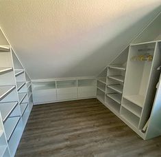 an attic bedroom with white shelving and wood flooring