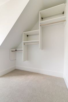 an empty room with white closets and open shelves in the ceiling, under a slanted roof