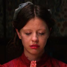 a woman with her eyes closed and hands folded in front of her face, praying