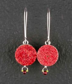 pair of red earrings with silver earwires and bead detail on black background