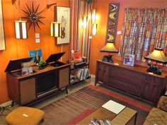 a living room with an orange wall and wooden furniture in the corner, along with two lamps on either side of the table