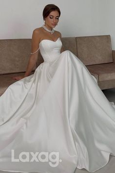 a woman in a white wedding dress sitting on a couch with her hands behind her back