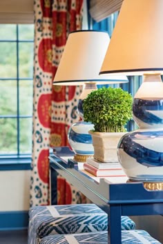 a blue table with two lamps and a potted plant sitting on top of it