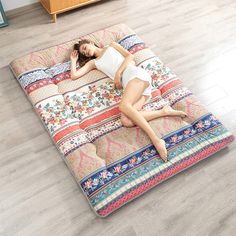 a woman laying on top of a multicolored bed in the middle of a room