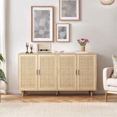 a living room with white walls and pictures on the wall above an entertainment center that has wicker doors