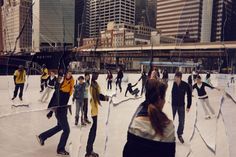 a group of people skating on an ice rink in the middle of a large city