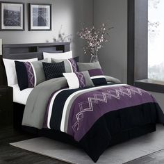 a bed with purple and black comforters in a room