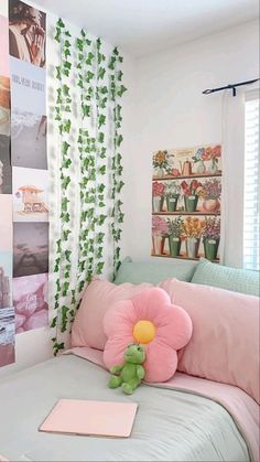 a pink flower sitting on top of a bed next to a green teddy bear and pillows