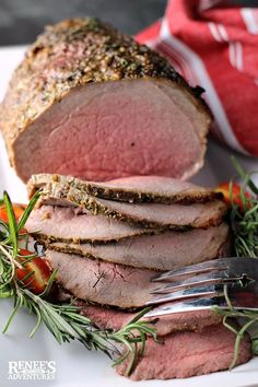 sliced roast beef on a white plate with fresh herbs