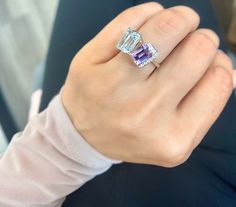 a woman's hand wearing a ring with an amethorate and diamond