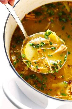 a ladle full of soup is being held by a person with a spoon in it