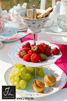 three tiered trays with strawberries, grapes and muffins on them