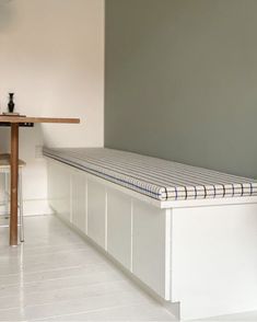 a white bench sitting in the middle of a room next to a table and chair