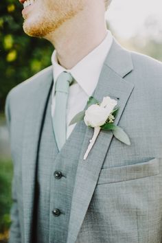 a man wearing a gray suit and white flower