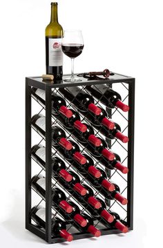 a wine rack with many bottles and glasses on the top, next to a bottle of wine