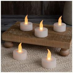 four white candles sitting on top of a wooden table