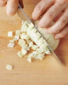 a person chopping onions with a knife on a cutting board