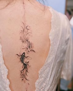 the back of a woman's neck with a bird and flower tattoo on it