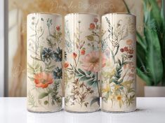 three vases sitting on top of a white table next to a potted plant