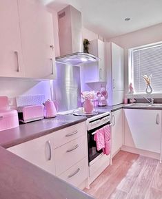 a kitchen with white cabinets and pink accessories