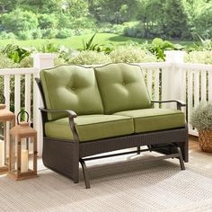 a couch sitting on top of a wooden floor next to a white fence with trees in the background