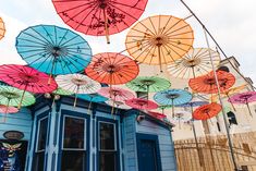 many colorful umbrellas hanging from the side of a building