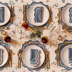 the table is set with blue and white plates, silverware, and wine glasses