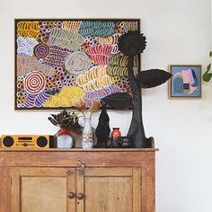 a wooden cabinet sitting in front of a painting on the wall