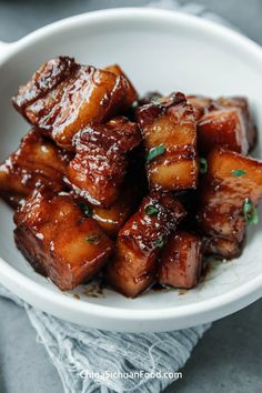 a white bowl filled with fried tofu and garnished with parsley on top