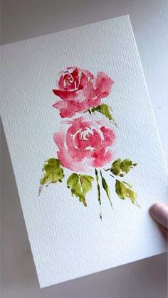 a hand holding up a card with watercolor roses on it and the paper is white