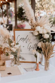 the table is set up with vases and flowers for guests to sign in front of