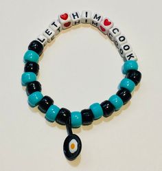 This rave kandi bracelet says "Let him cook" with an egg frying pan on it.  You may change the words or color of the beads if you'd like. Bed Bracelet Ideas, Rave Candy Ideas, Kandi Collar, Funny Bracelet Ideas, Kandi Quotes, Kandi Sayings, Kandi Phrases, Festival Trinkets, Funny Kandi Bracelets