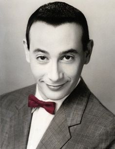 a black and white photo of a man in a suit with a red bow tie