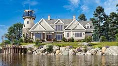 a large house with a lighthouse on the top of it's roof next to a body of water