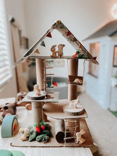 a doll house made out of cardboard on top of a table with other toys and decorations